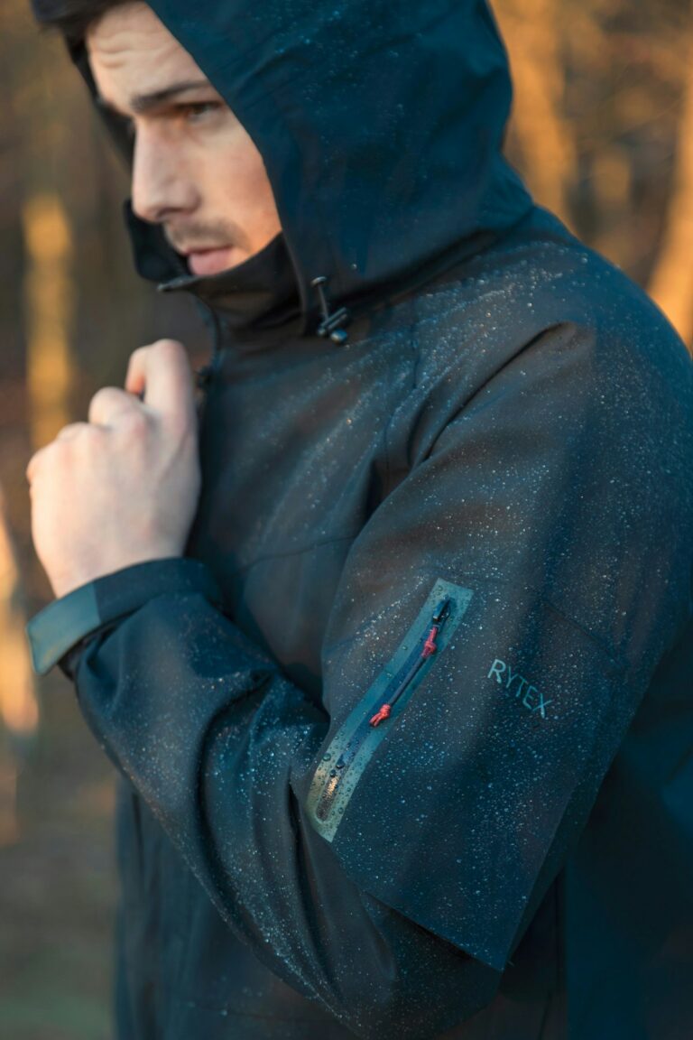 Rain jackets for hiking in Nairobi – hiker in a hooded rain jacket standing in the woods